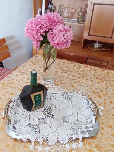 a table with a vase of pink flowers and a bottle of perfume at Rustic house Hutovo Blato in Čapljina