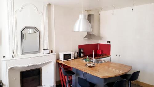 une cuisine avec une table en bois et une cheminée dans l'établissement La Couronne - 2 chambres près du marché, à La Rochelle