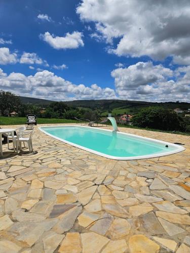 a large swimming pool with a table and chairs at Chalés Vila Carrancas - Ao lado do centro com piscina, cozinha completa e muita tranquilidade in Carrancas