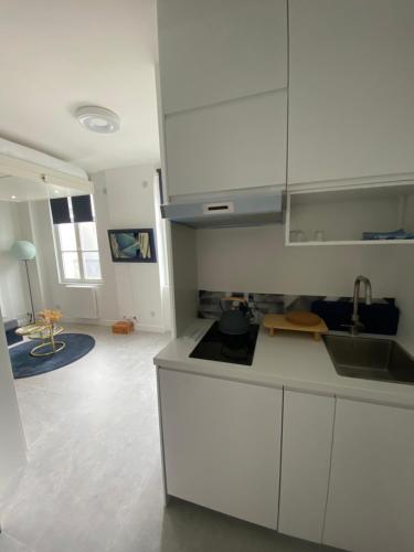 une cuisine avec des armoires blanches et un salon dans l'établissement Studio confortable, à Pantin