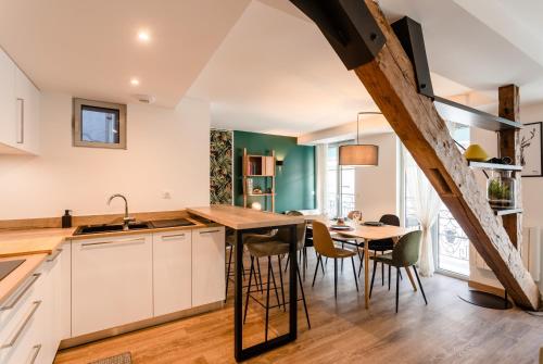 une cuisine avec des armoires blanches et une table avec des chaises dans l'établissement Appartement de charme pour 5P, à Cauterets