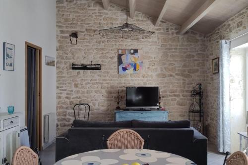 un salon avec un canapé et une télévision dans l'établissement Maison de charme rénovée proche océan Domino, à Les Sables Vignier