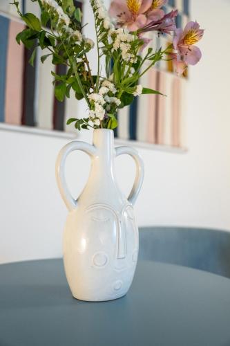 a white vase with flowers in it on a table at Sella&Mosca Casa Villamarina in Alghero