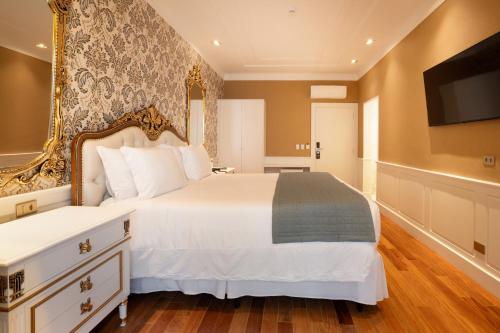 a bedroom with a large bed and a flat screen tv at Pousada Luis XV in Campos do Jordão