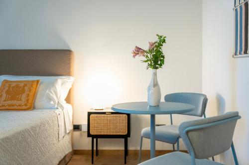 a table with a vase of flowers on it next to a bed at Sella&Mosca Casa Villamarina in Alghero