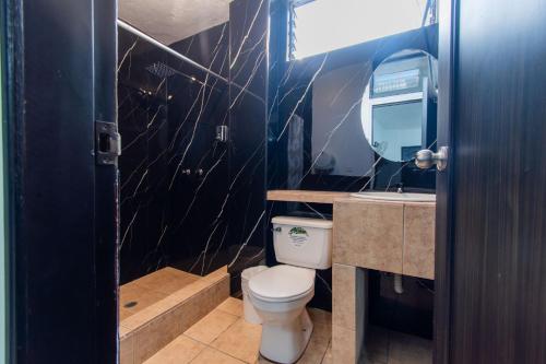 a bathroom with a toilet and a sink at Hotel el Marqués in Santo Domingo de los Colorados