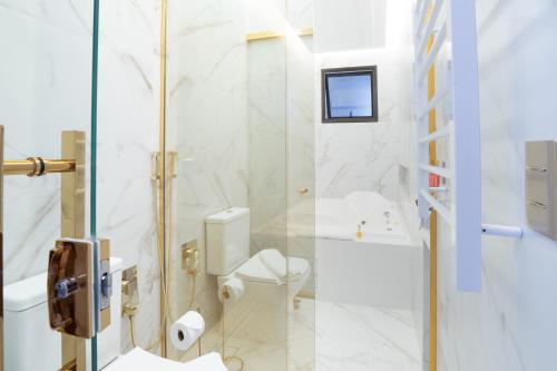 a white bathroom with a toilet and a shower at Pousada Luis XV in Campos do Jordão
