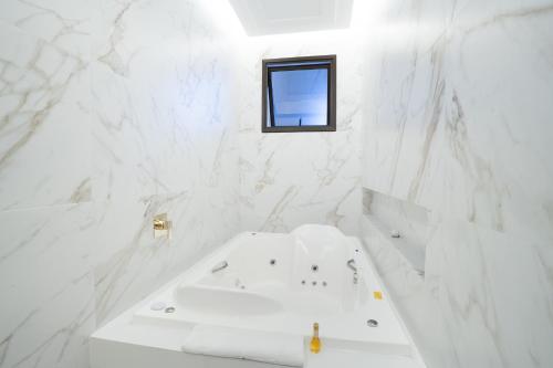 a white bathroom with a tub and a window at Pousada Luis XV in Campos do Jordão