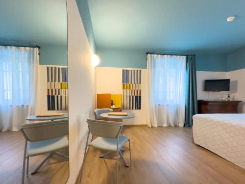 a bedroom with a bed and two tables and chairs at Sella&Mosca Casa Villamarina in Alghero