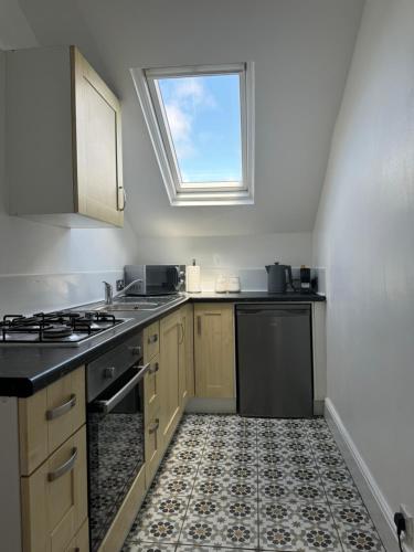 a kitchen with a sink and a stove and a window at The Eaves - Victorian second floor, open plan apartment in Southport
