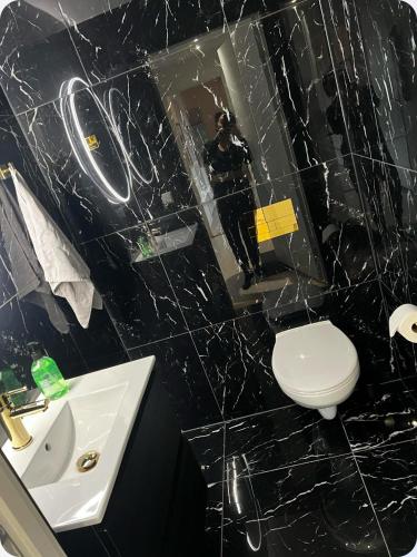 a black tiled bathroom with a toilet and a sink at Moderne Leilighet in Stord