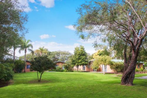 a green yard with trees and houses at Sandy Bay Holiday Park in Busselton
