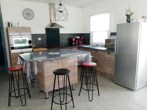 eine Küche mit einer Theke mit Hockern und einem Kühlschrank in der Unterkunft location bord de mer La Plaine sur mer in La Plaine-sur-Mer