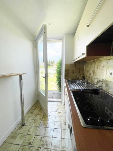une cuisine avec une porte ouverte sur un patio dans l'établissement Appartement 11 en duplex - LES SUITES DE ROBINSON - Résidence avec piscine en bord de Siagne, à Mandelieu-La-Napoule, à Mandelieu-la-Napoule