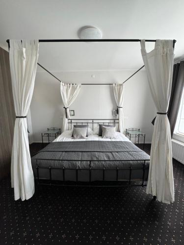 a bedroom with a large bed with white curtains at Ouwe Schuure in Sluis