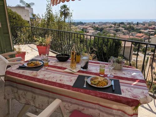 une table avec deux assiettes de nourriture sur un balcon dans l'établissement Oasis de sérénité avec vue mer imprenable, à Cagnes-sur-Mer
