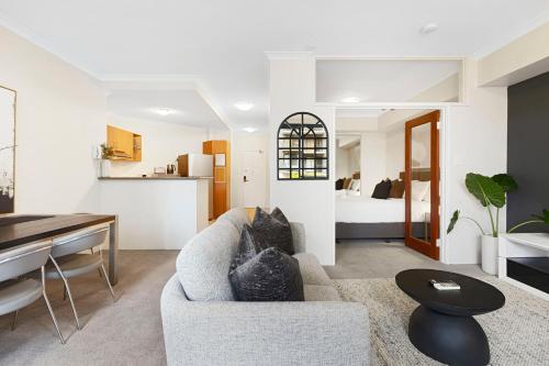 a living room with a couch and a bedroom at Executive Elegance Stylish 1BR Suite on Hay St in Perth