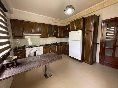 a kitchen with wooden cabinets and a white refrigerator at Batroun Green Serenity 2 BED - 24hr Electricity in Batroûn
