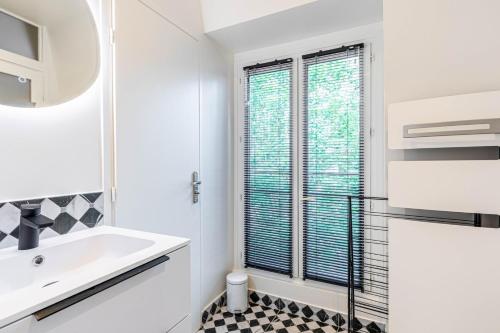 une salle de bain blanche avec un lavabo et une fenêtre dans l'établissement GuestReady - Nice urban hideout near Montmartre, à Paris