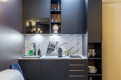 - une cuisine avec des placards noirs et un évier dans l'établissement GuestReady - Nice urban hideout near Montmartre, à Paris