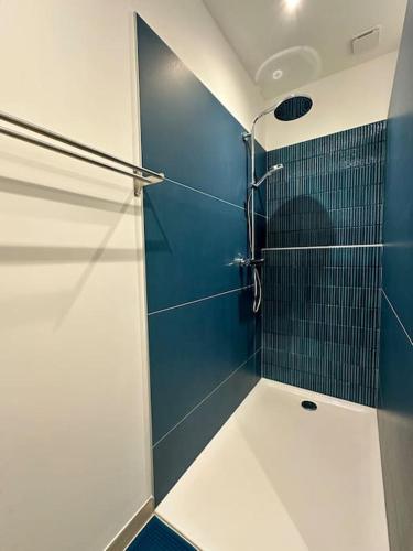 La salle de bains est pourvue d'une douche avec un mur bleu. dans l'établissement Villa Paquerette avec spa, à Nîmes