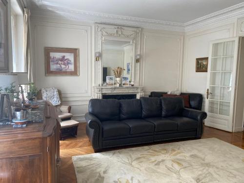 - un salon avec un canapé noir et un miroir dans l'établissement Paris - Appartement - 16eme, à Paris