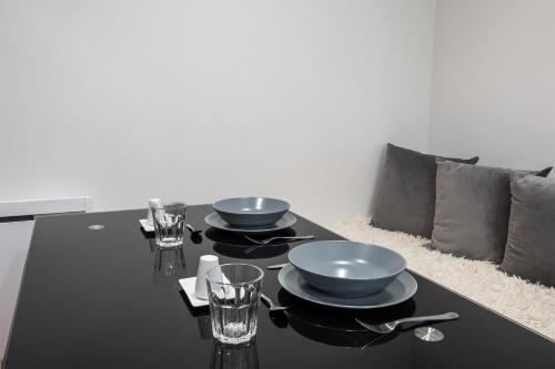 une table noire avec des assiettes et des verres dans l'établissement Appartement Térreo - Welkeys, à Paris