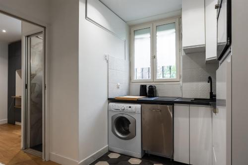 une cuisine blanche avec une machine à laver à l'intérieur dans l'établissement Appartement Térreo - Welkeys, à Paris