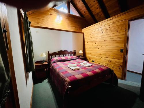 ein Schlafzimmer mit einem Bett in einem Holzzimmer in der Unterkunft Cuncumen Casa de Montaña in Villa La Angostura