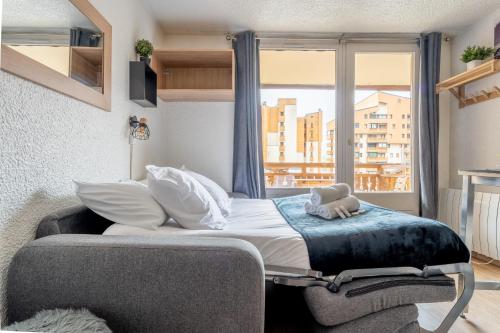 un lit dans une chambre avec une grande fenêtre dans l'établissement Ski In-Out - Heart of Val Thorens Convenient Flat, WiFi 92, à Val Thorens