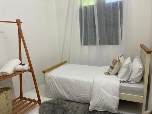 a bedroom with a bed with white sheets and a window at Nashu House Stone Town in Ngambo