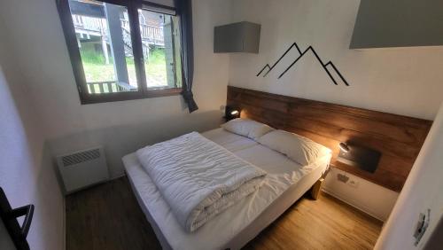 une chambre avec un lit dans une pièce avec une fenêtre dans l'établissement Appartement 4 à 6 personnes - Chalets d'Aurouze - La Joue du Loup, à Saint-Étienne-en-Dévoluy