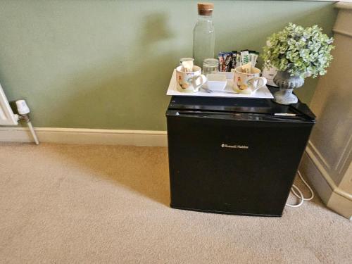 a black cabinet with a bottle and cups and flowers at The Casterbridge in Dorchester