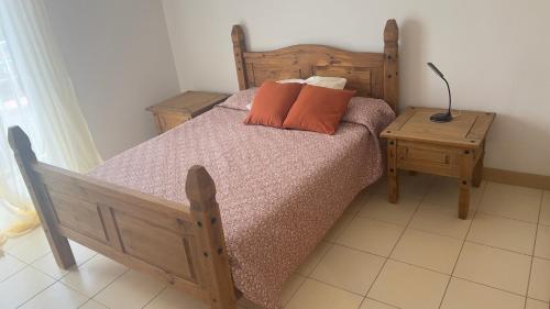 a bedroom with a wooden bed with two orange pillows at Apartamento T2 equipado Vila Verde in Santa Maria