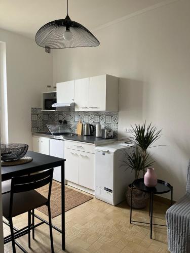 une cuisine avec des armoires blanches et une table dans une pièce dans l'établissement T2 Alfortville, à Alfortville