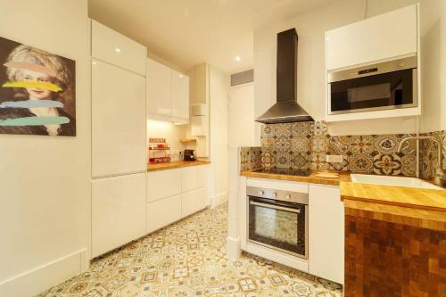 une cuisine avec des placards blancs et une cheminée dans l'établissement Residence Reine - Boulogne - Paris, à Boulogne-Billancourt