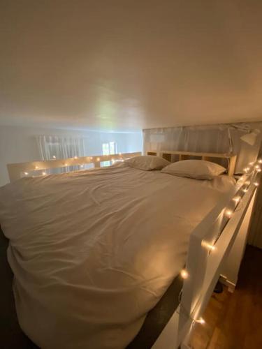 - une chambre avec un lit blanc éclairé dans l'établissement Appartement de charme près du Stade de France, à Saint-Denis
