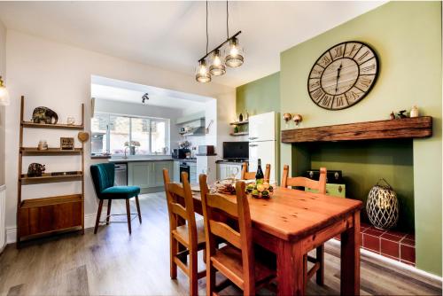 une cuisine et une salle à manger avec une table en bois et une horloge dans l'établissement Shorethwaite, à Amble