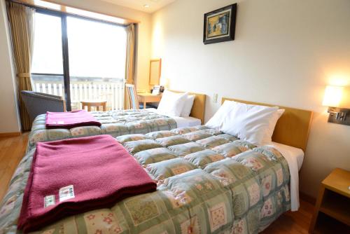 a hotel room with two beds and a window at Iwakuni Kokusai Kanko Hotel in Iwakuni