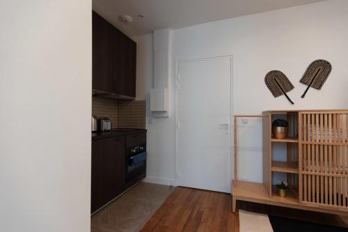 - une cuisine avec des murs blancs et un réfrigérateur blanc dans l'établissement Joli studio proche de paris -pantin, à Pantin