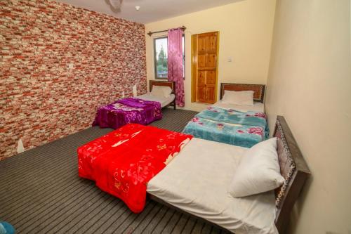 a bedroom with two beds and a brick wall at Yak Sarai Hotel & Restaurant in Skardu