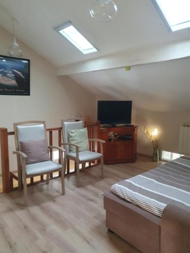 a bedroom with two chairs and a bed and a tv at MAISON PROCHE PLAGE SUR BASSIN D ARCACHON in Andernos-les-Bains