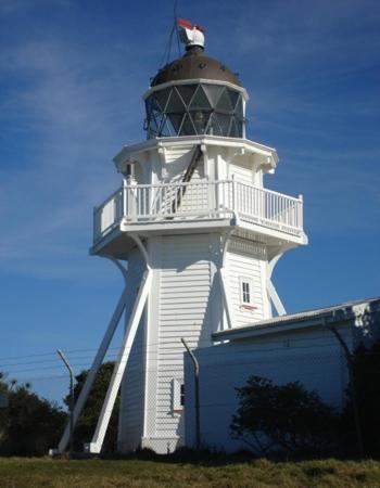 a lighthouse with a building in front of it at Noah's Boutique Accommodation Moeraki in Moeraki