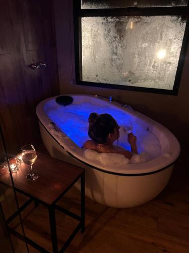 a woman in a bath tub with a glass of wine at Chalés do Mato Dentro in Paraisópolis