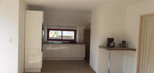 une cuisine avec des armoires blanches et une fenêtre dans l'établissement Maison avec mare, à Solesmes