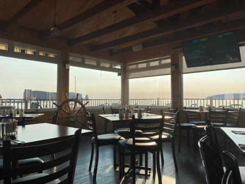 a dining room with tables and chairs and windows at Hotel-Motel Fleur de Lys in Perce