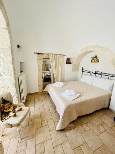 a bedroom with a large bed and a chair at Trulli Ada in Noci