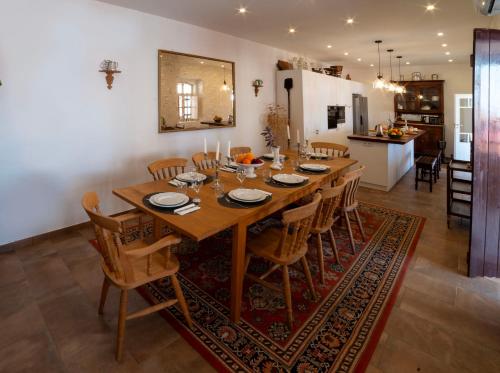 a large wooden table with chairs and a kitchen at Casa das Amendoeiras in Silves