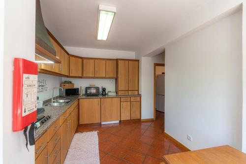 a kitchen with wooden cabinets and a red tile floor at Atlantic Nest Coimbra in Coimbra
