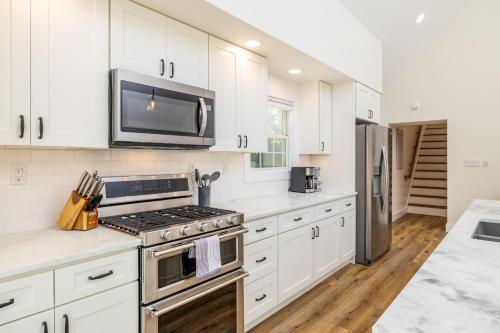 a kitchen with white cabinets and a stove and a microwave at Tranquil Mountain Escape Luxurious 2 Bedroom 2 Bath Cottage on 9 Acres in Maryville